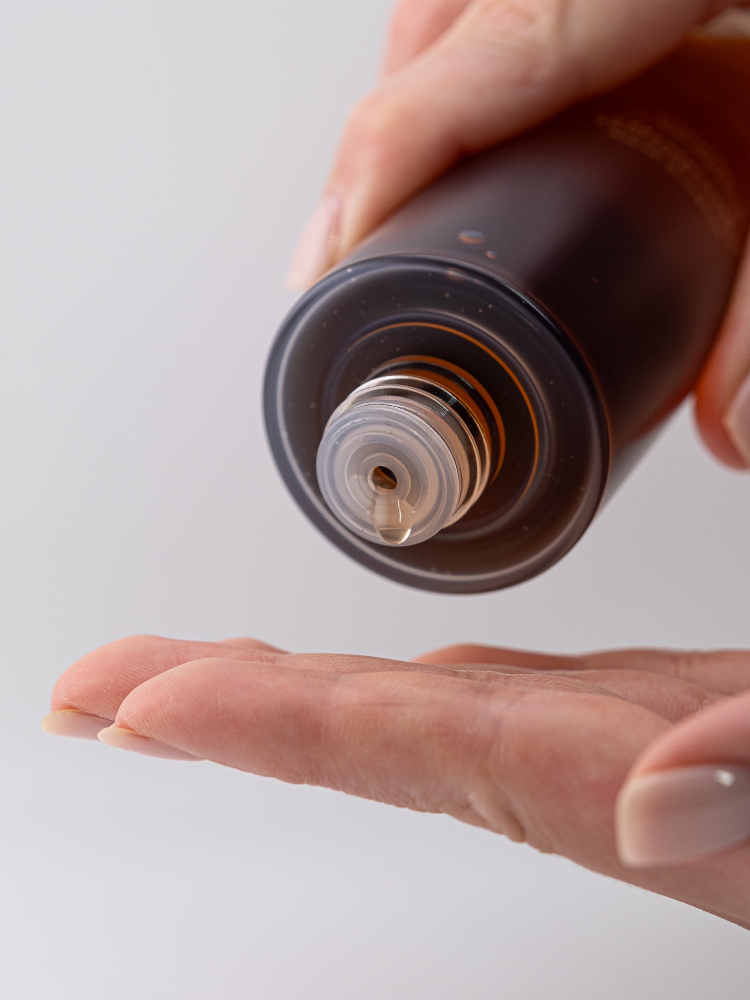 Hand holding a ginseng essence water bottle with a single drop into a hand