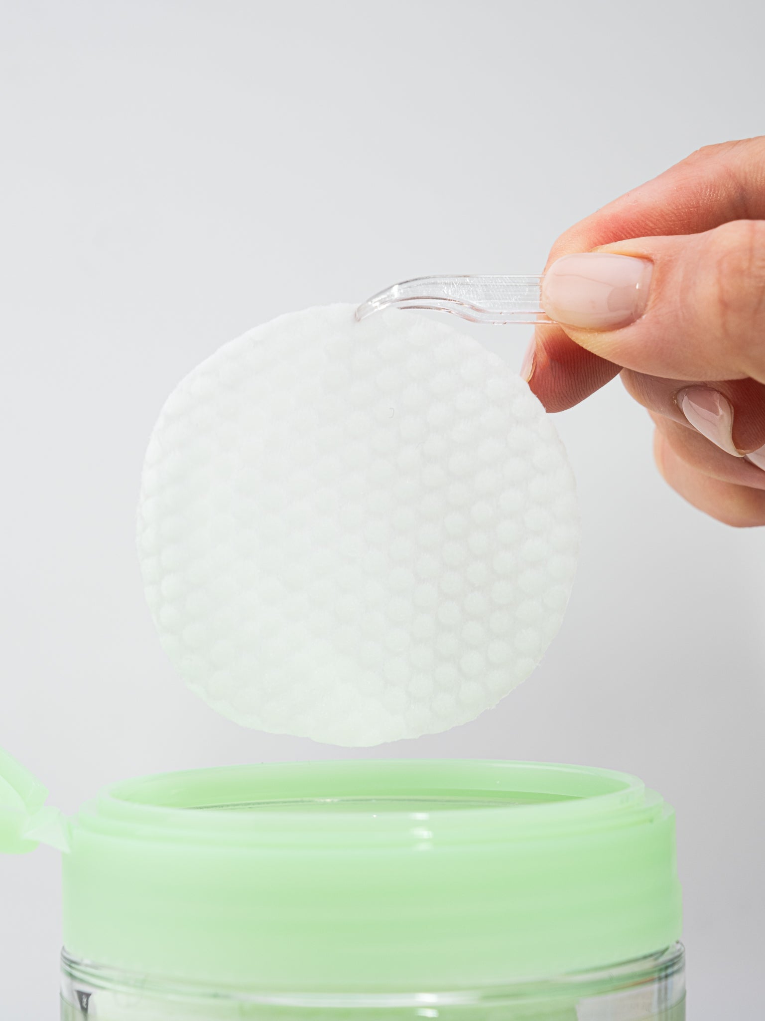 Hand with a single Torriden Balanceful Toner Pad on a white background