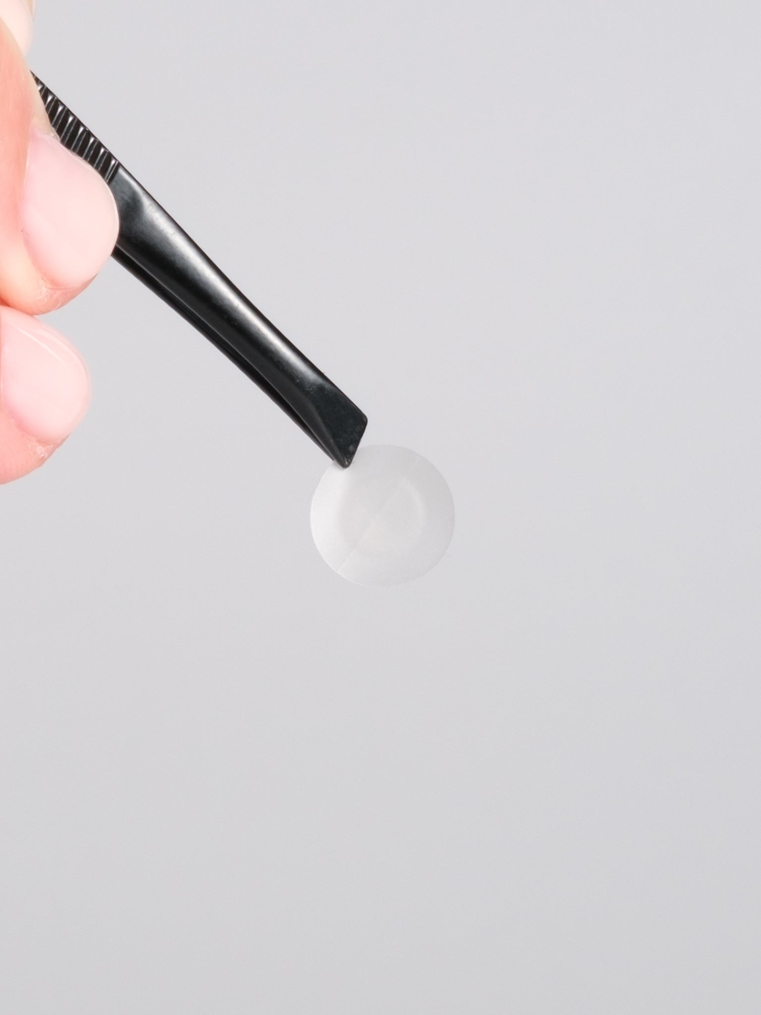 A single thin, clear VT PRO Cica hydrocolloid spot patch held on tweezers