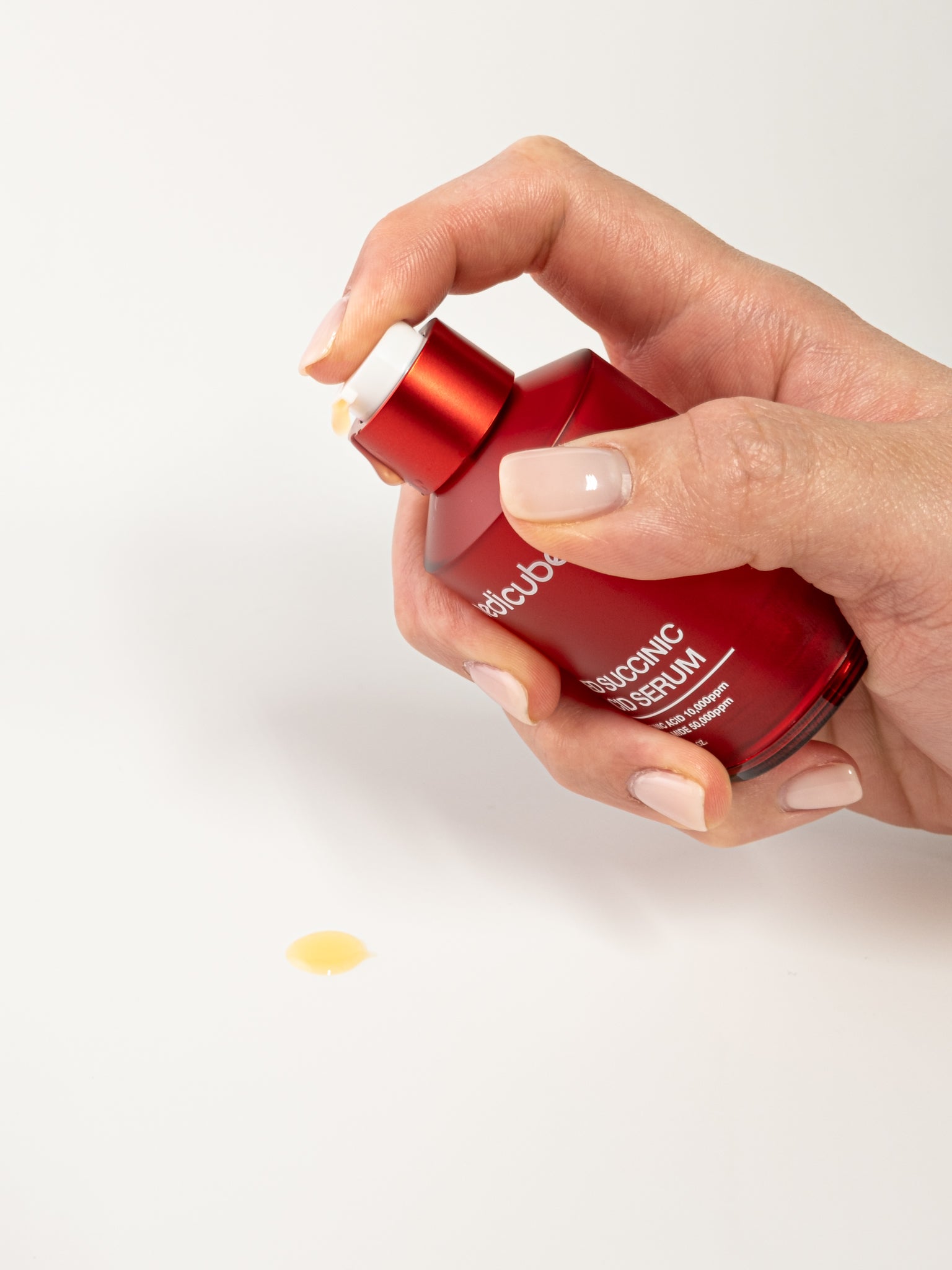 Medicube red succinic acid serum being pumped on a white background