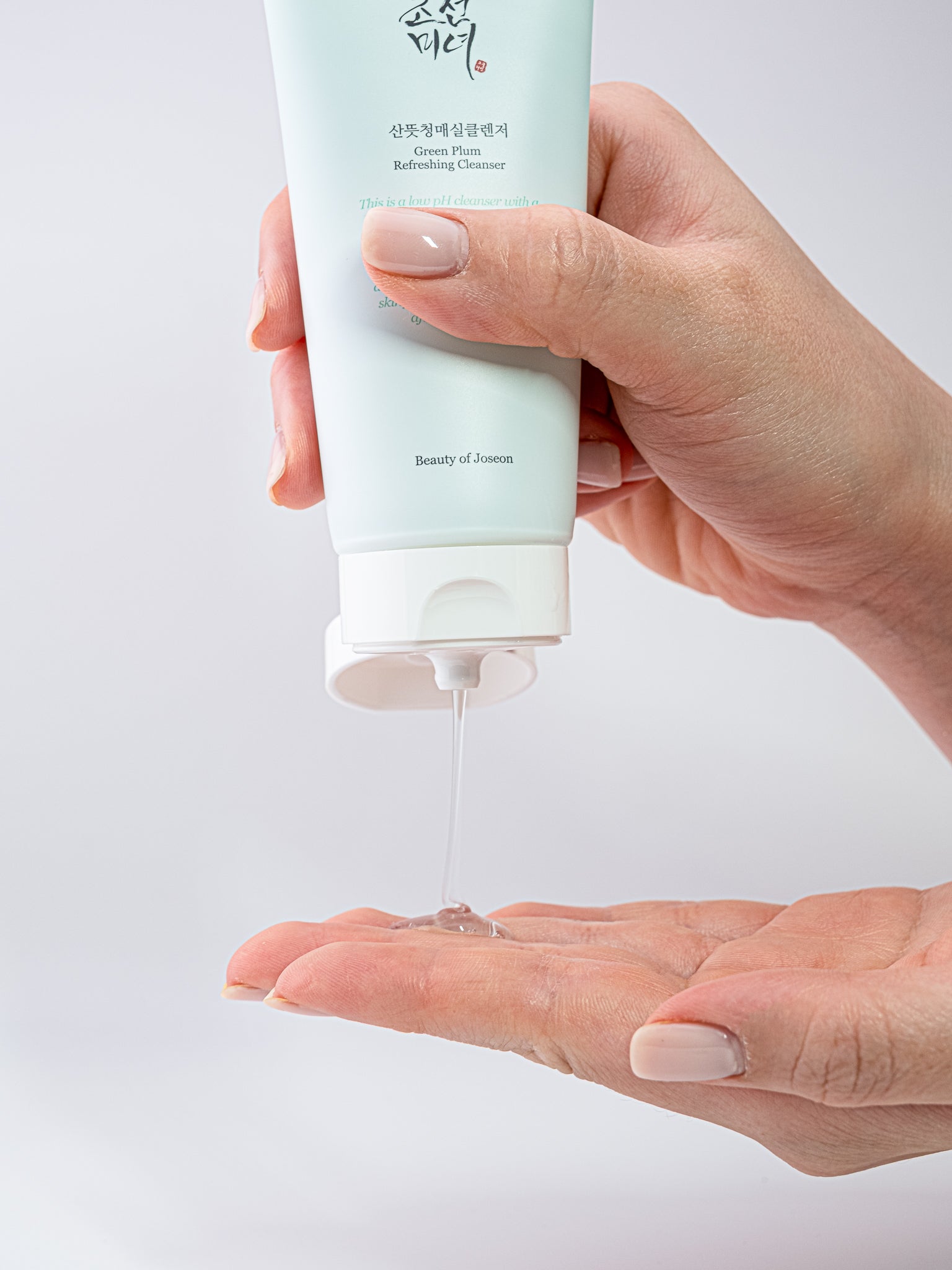 Hand squeezing Green plum refreshing cleanser into hand