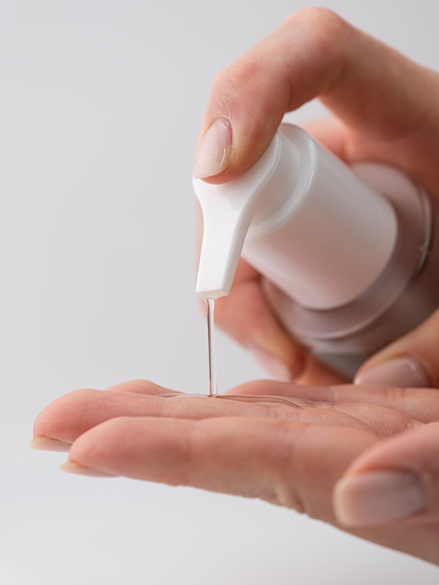 Hand pressing down on pump of haru haru wonder moisture deep bottle with product on hand below