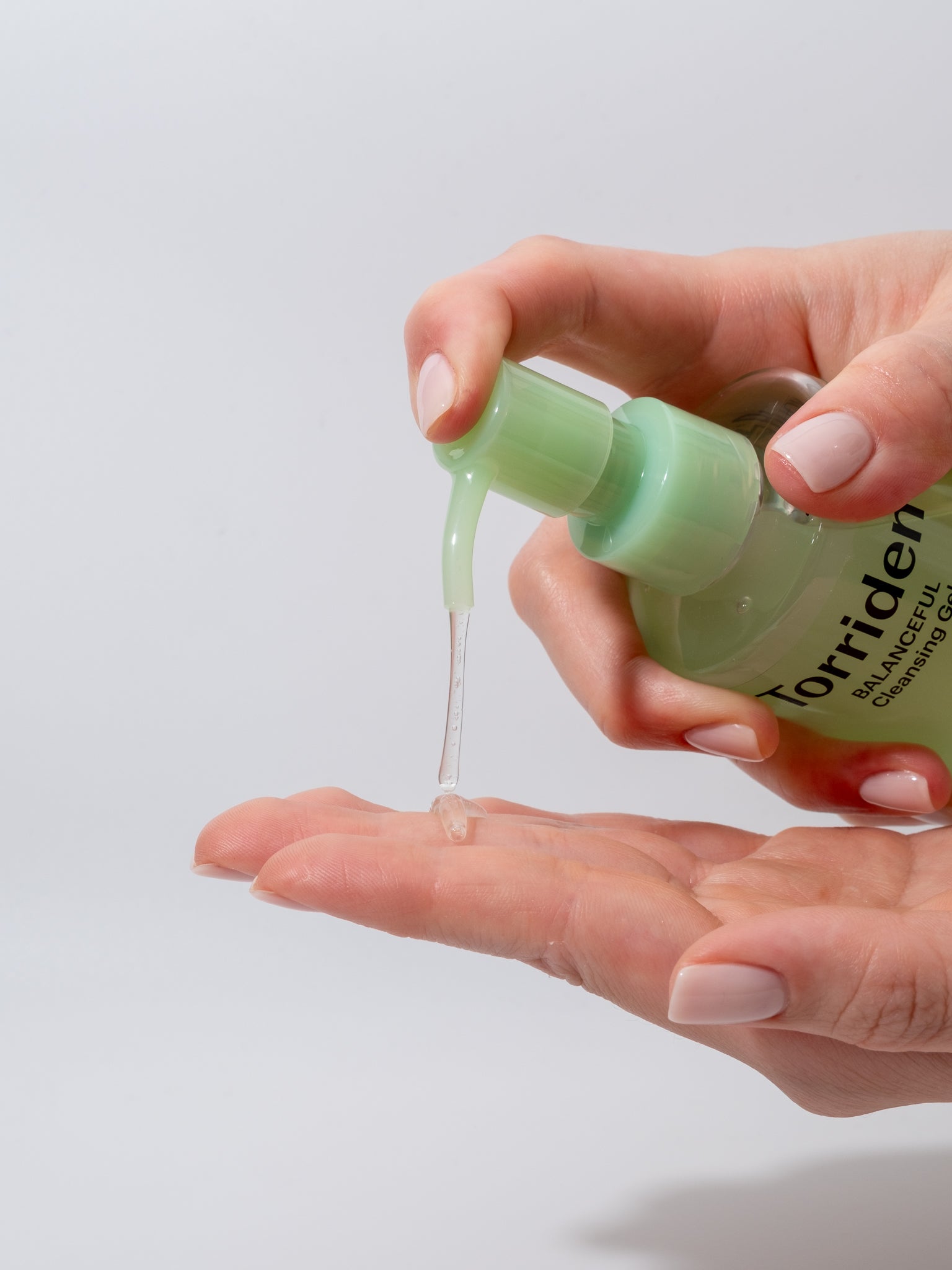Hand holding a bottle of Torriden balanceful cleansing gel with a clear background