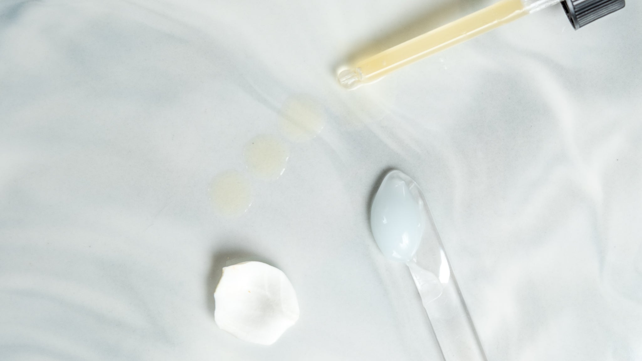 White plate with a small amount of yellowish liquid, a spoon, and a bottle on a white background