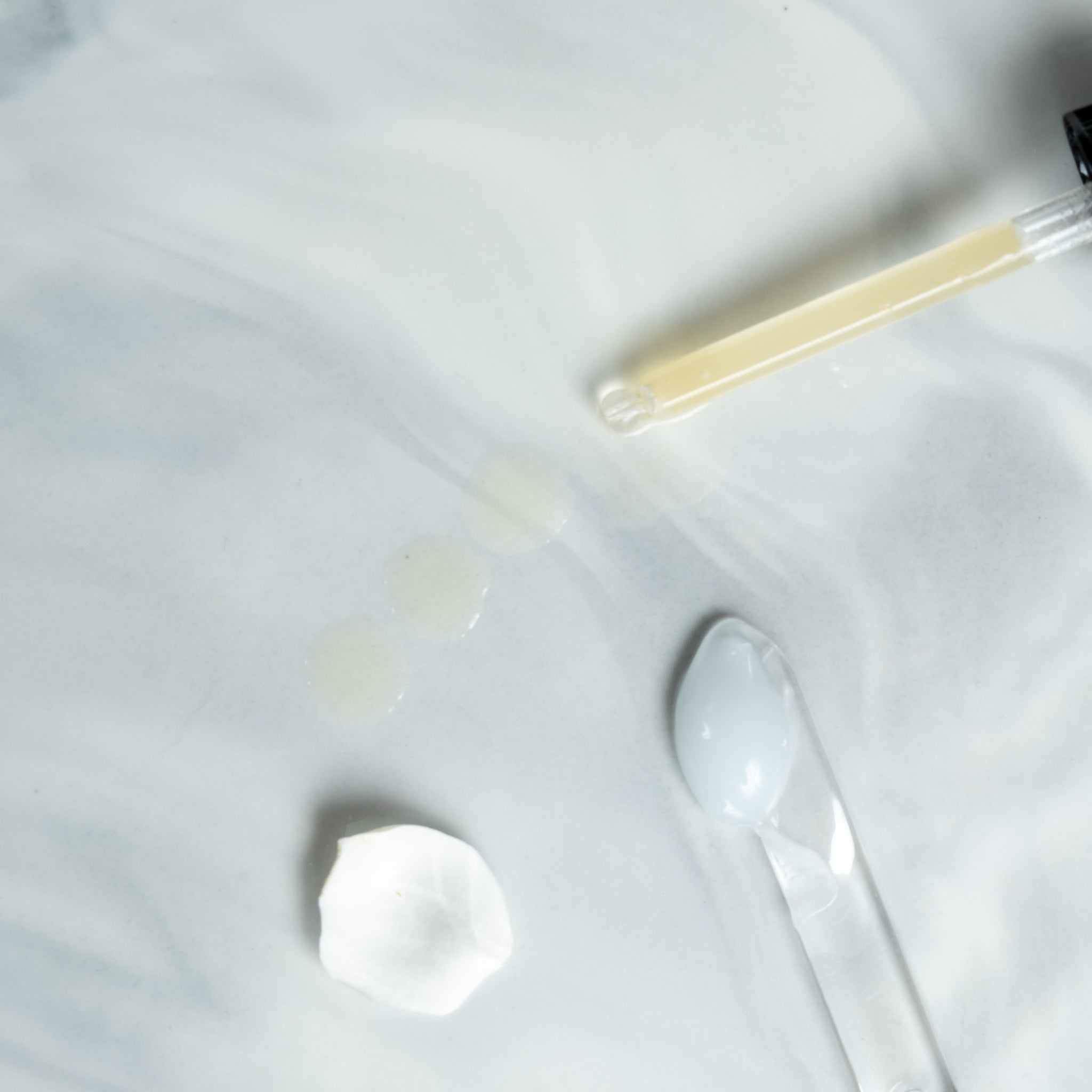 Serum dropper, moisturising cream on blue background