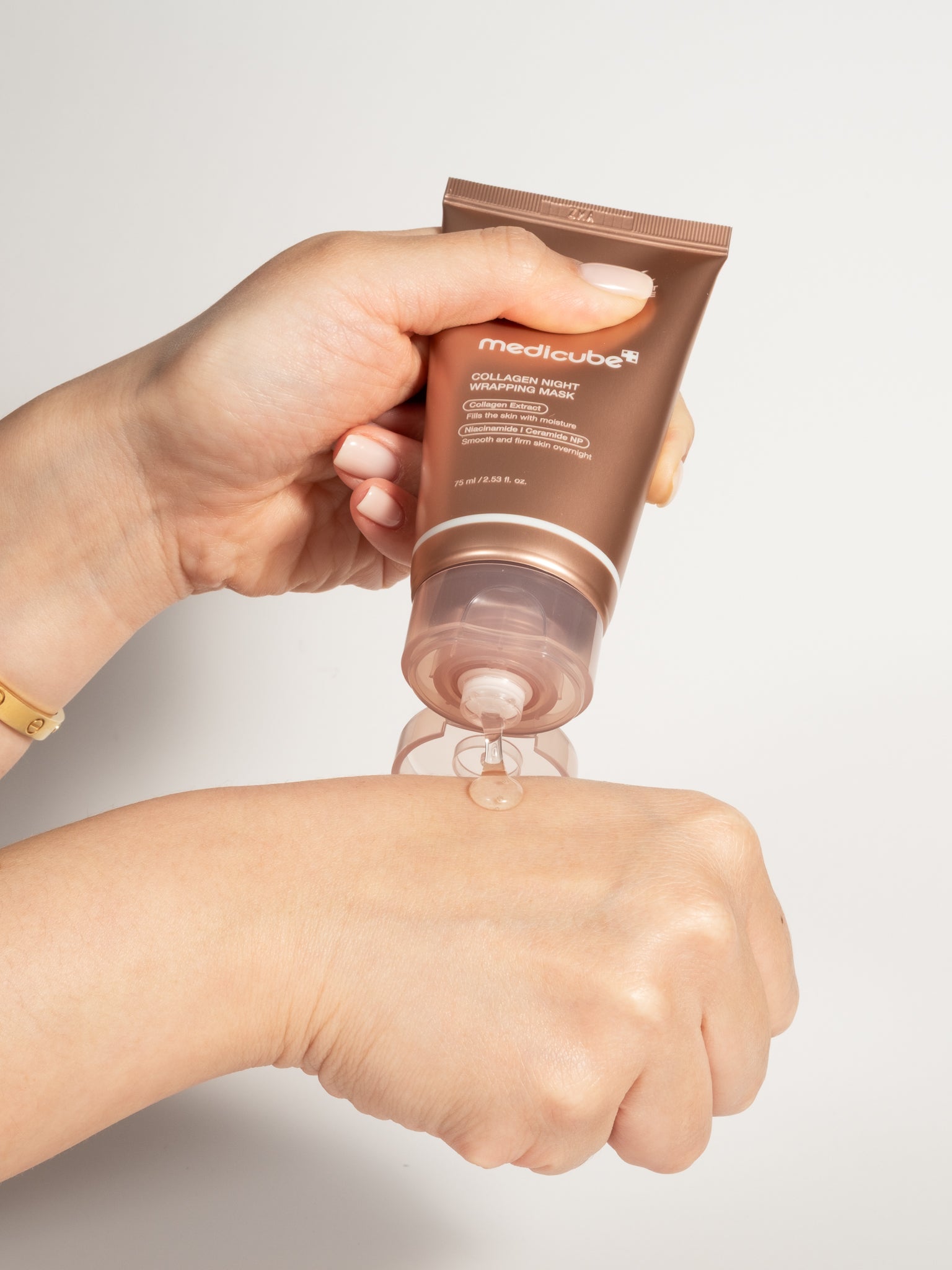 Medicube Collagen Night Wrapping Mask being squeezed from its tube onto the back of a hand.