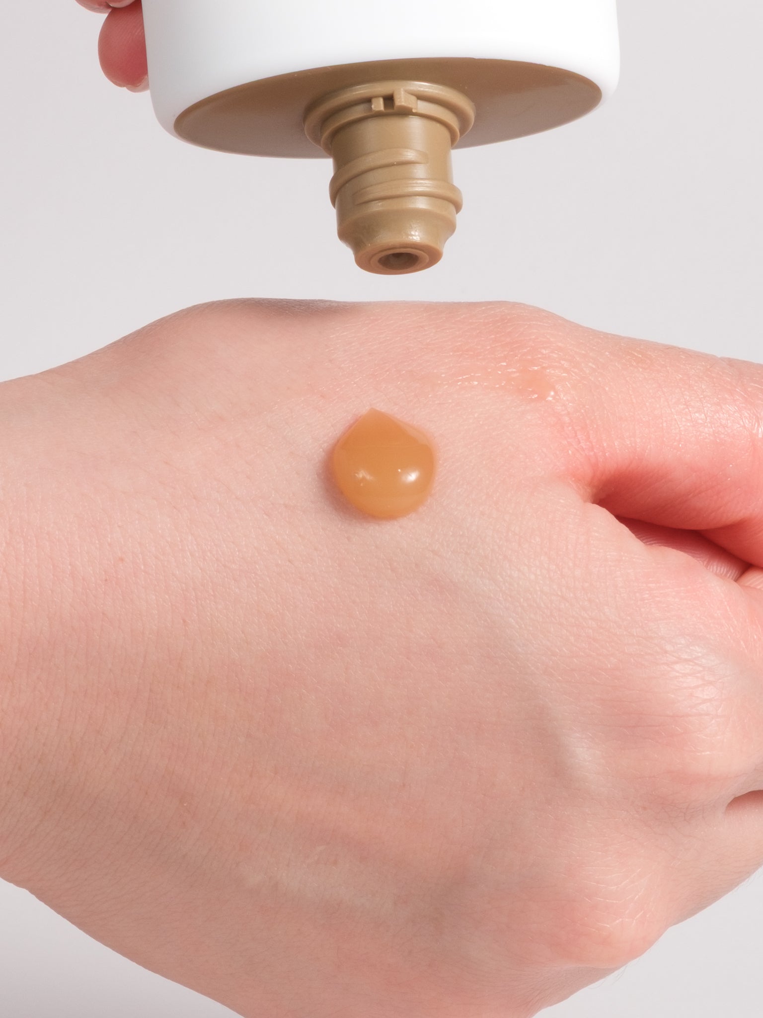 SKIN1004 Madagascar Centella Soothing Cream dispensing an amber gel drop onto the back of a hand