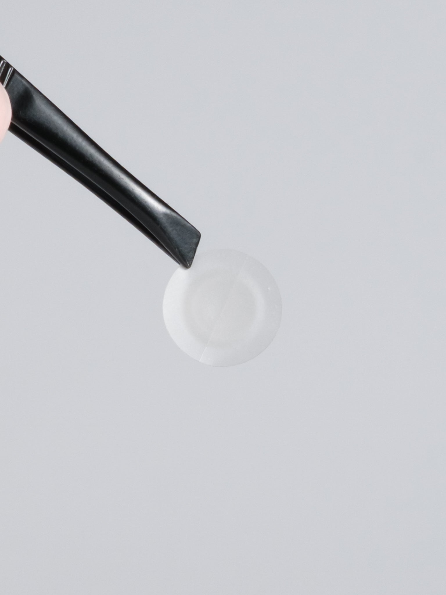 Close-up of a clear VT PRO Cica spot patch on tweezers, ready to apply over a blemish