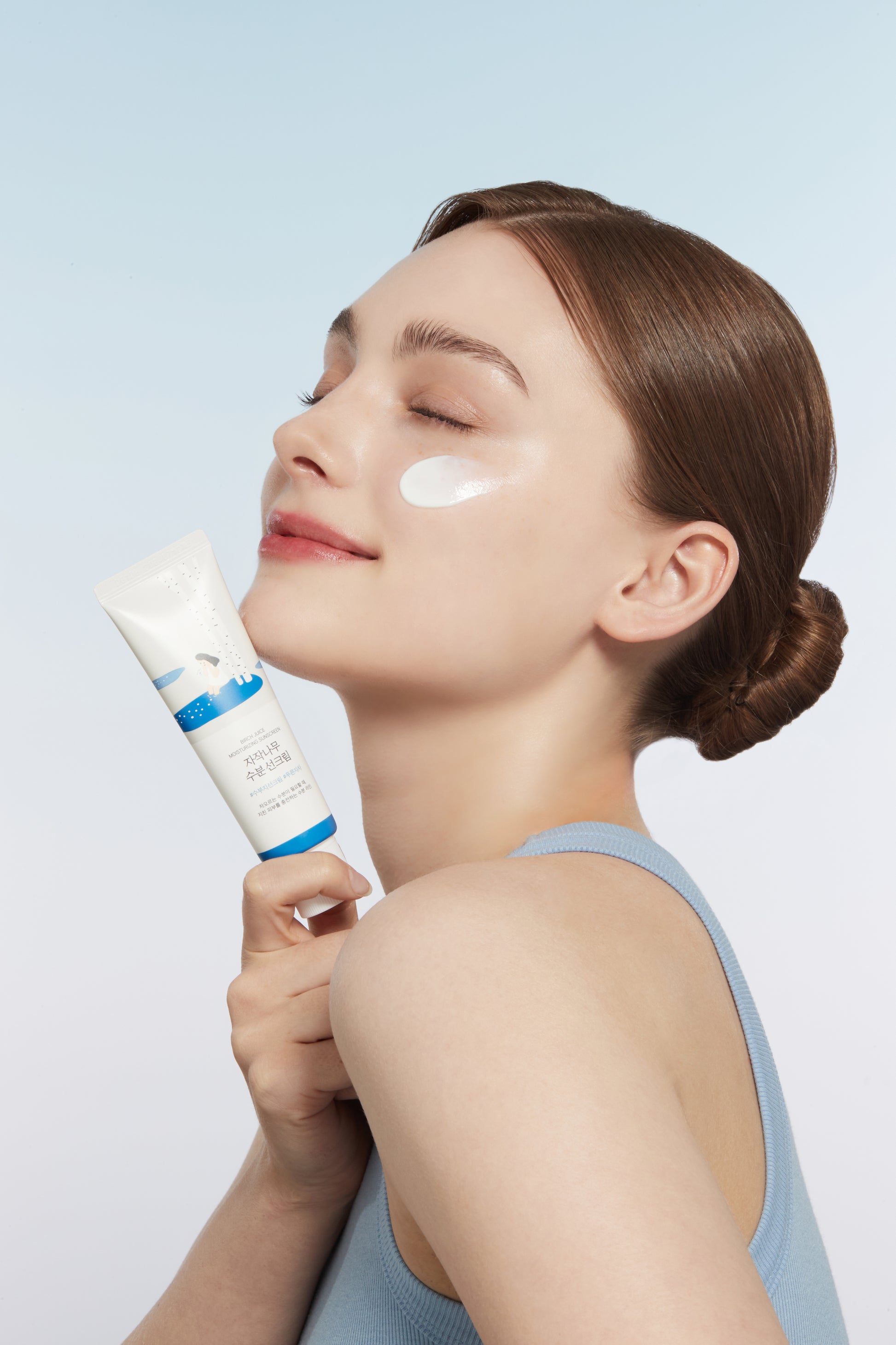 Model holding Roundlab birch juice moisturizing sunscreen with texture